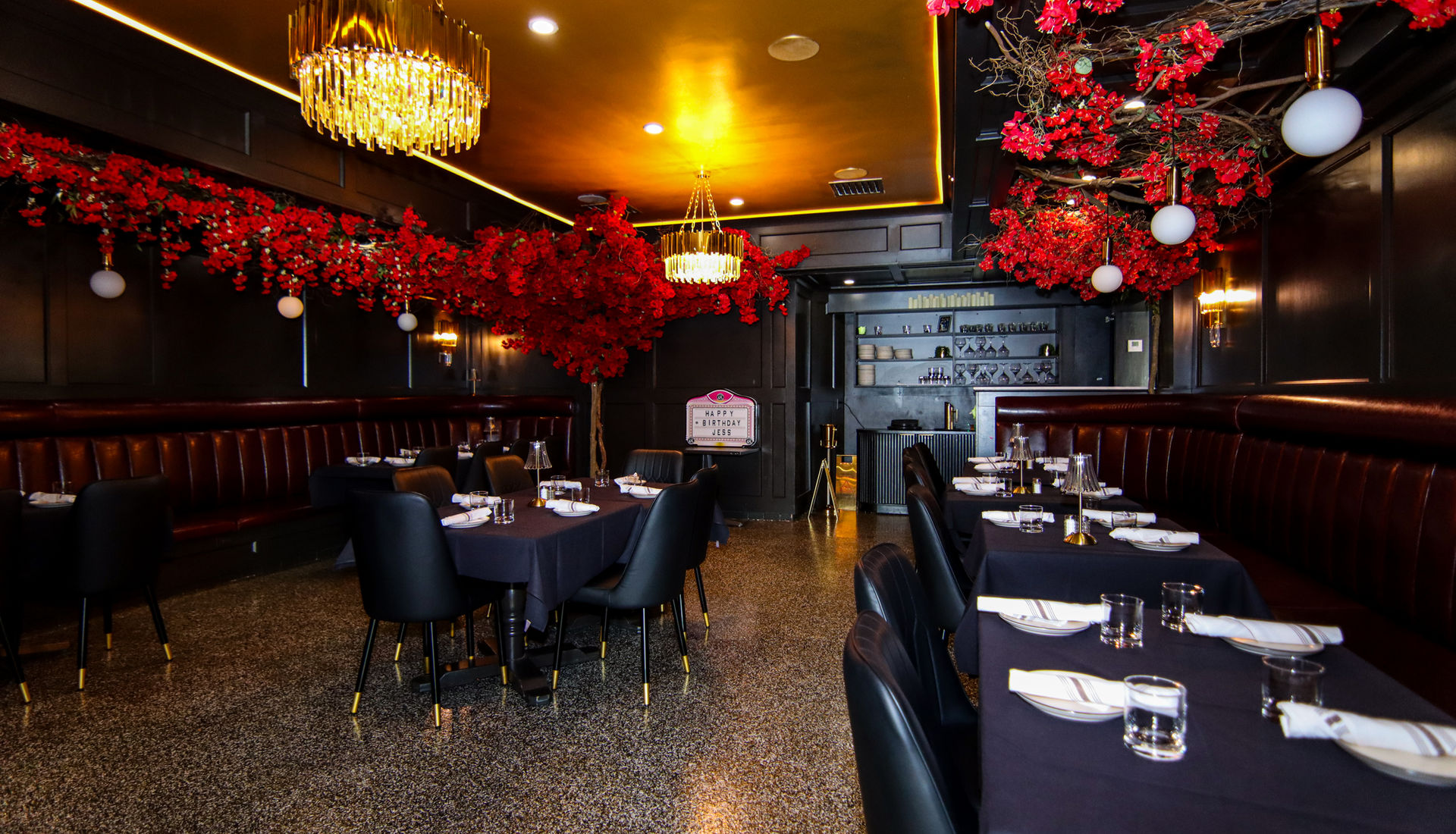 Fuego Steakhouse & Bar dining room with red florals and gold chandeliers, set for the evening