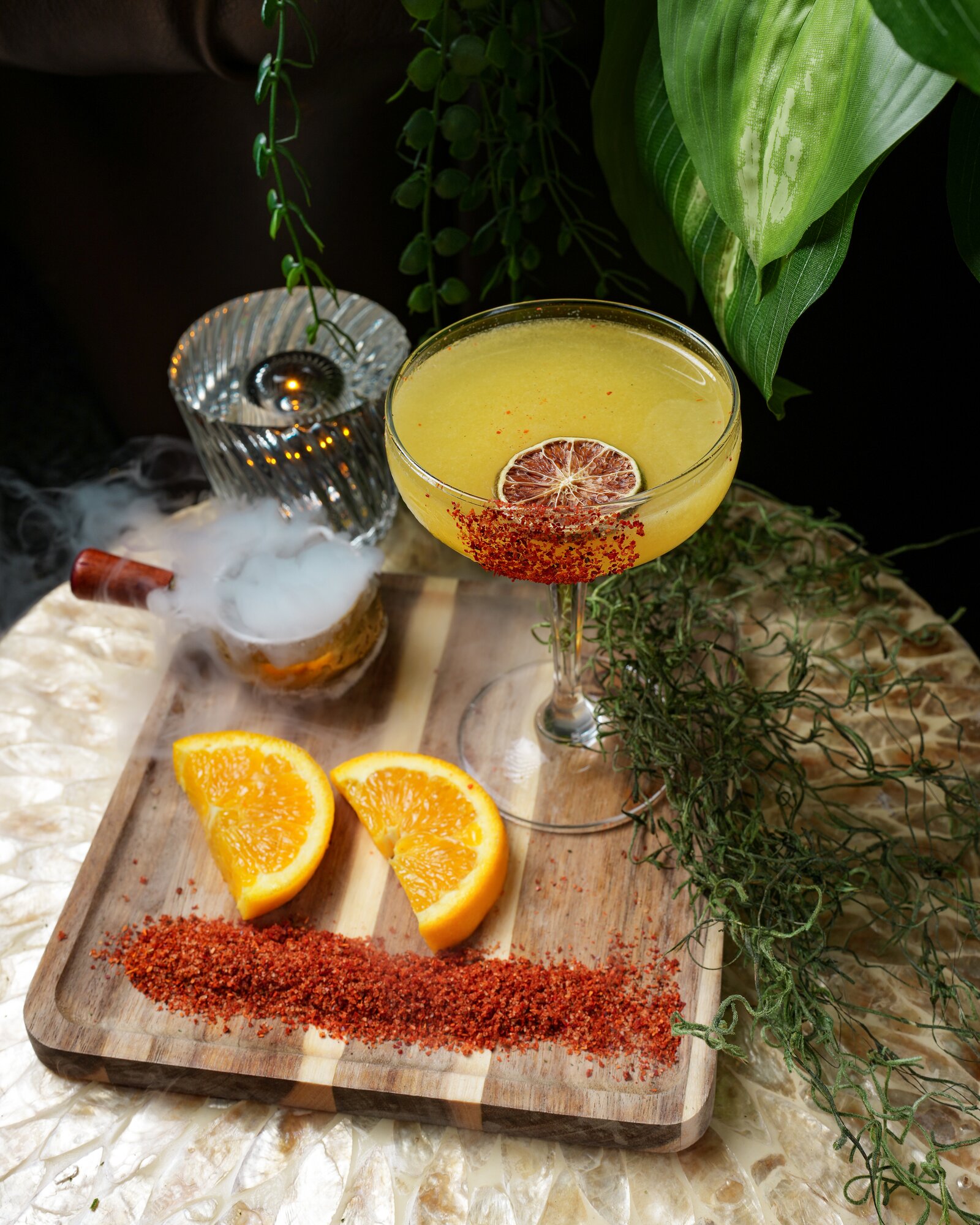 A dried-lime coupe cocktail with chili rim and orange slices