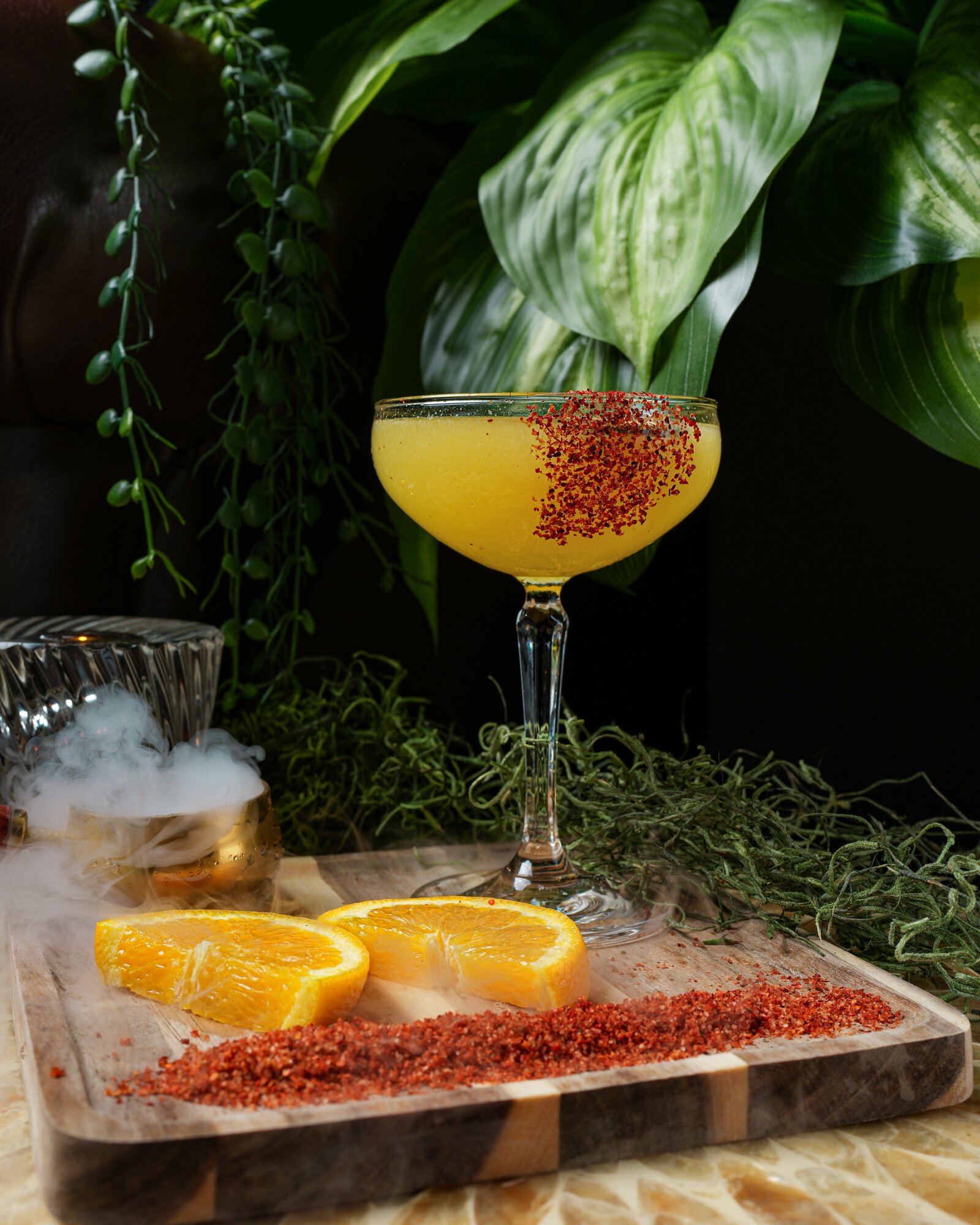 A golden margarita with a chili rim and dry-ice smoke