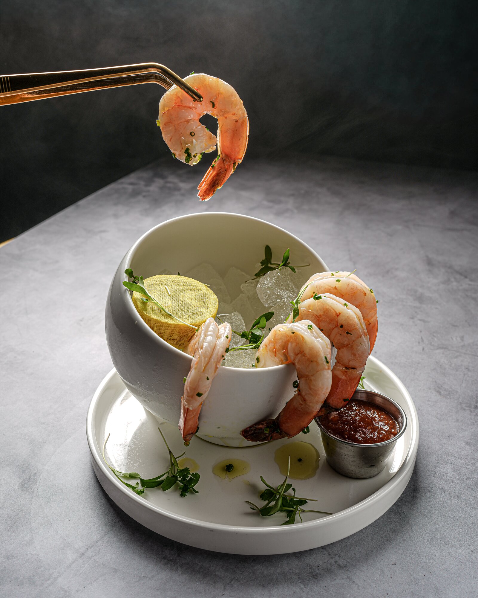 Server plating a shrimp cocktail with gold tongs