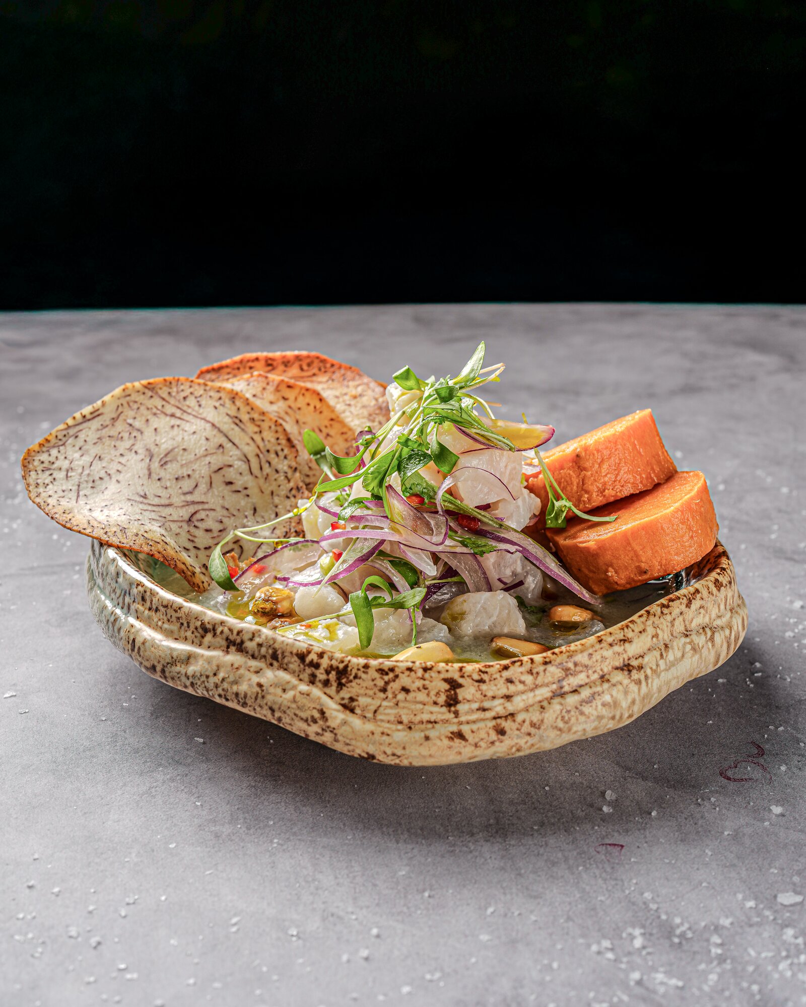Ceviche with taro chips and sweet potato in a rustic bowl
