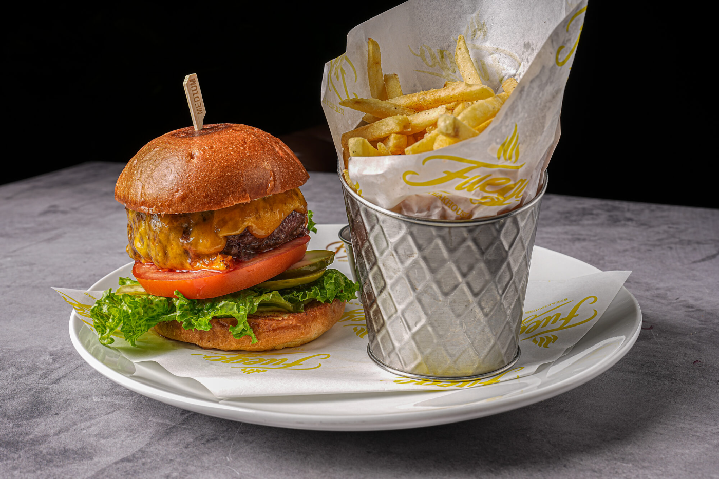 Signature burger with lettuce, tomato and a basket of fries