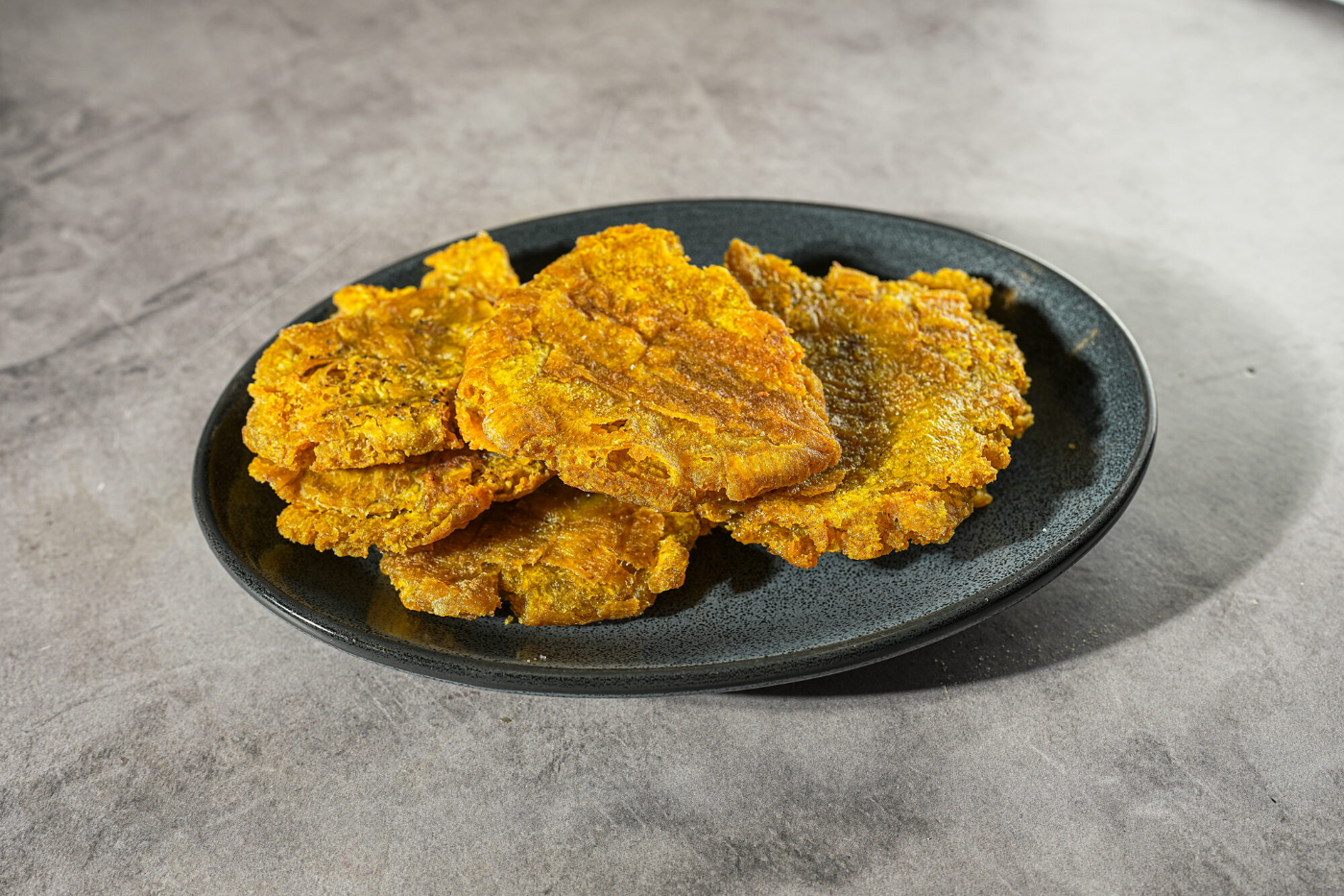 Golden tostones in an oval serving dish