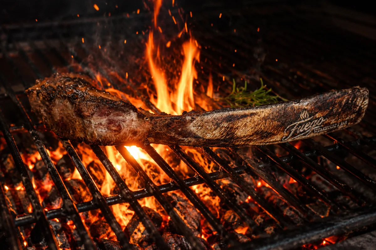 Horizontal branded Fuego tomahawk steak finished over open flame